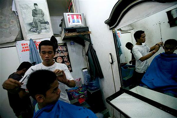 President Obama's address plays as an Indonesian youth has his hair cut.